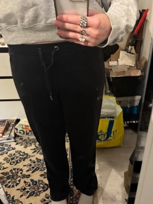 Svarta mjukisbyxor från Gina Tricot - Svarta mjukisbyxor från Gina Tricot med snörning i midjan. Byxorna har en rak passform och är tillverkade i ett mjukt material som känns skönt mot huden. Perfekta för chill dagar eller när du vill vara bekväm. Snöret går förmodligen ett knyta upp men det är en hård knut som jag själv valt att inte försöka få upp. 