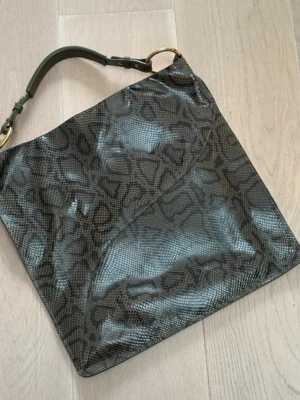 ATP Atelier väska ormskinn - ATP Atelier väska ormskinn  Säljer denna unika ATP väska i svart-grönt ormskinnsmönster. Inköpt på sample sale. Väskan är i mycket fint skick . Passar perfekt som skolväska eller jobbväska! Rymlig och passar laptop.  Mått: 38×40cm