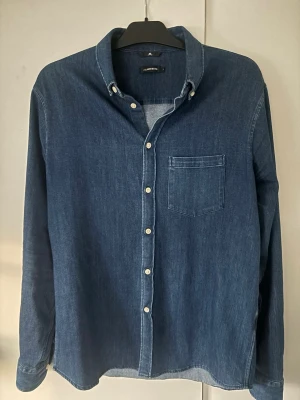 Helt ny J.lindeberg Jeanskjorta  - Helt ny sjukt snygg stilren och skön populör j.lindeberg Jeanskjorta i storlek L sitter som m. Inga defekter alls utan helt ny! Sjukt snygg på och passar till allt av högsta kvalite!