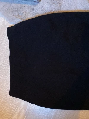 Svart pennkjol med dragkedja - Säljer en svart pennkjol i klassisk modell med en snygg silverfärgad dragkedja bak. Kjolen har en rak och tight passform som ger en stilren siluett. Perfekt att matcha med en crop top eller en oversized tröja. Storlek M