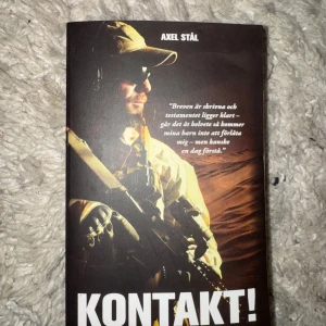 Kontakt! av Axel Stål - En spännande roman av Axel Stål om en svensk officers erfarenheter i specialstyrkorna och kampen mot terrorismen i Irak. Boken är i pocketformat med ett omslag i bruna och beige toner, prydd med en soldat i militärutrustning och gevär.