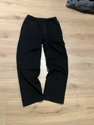 Svarta Pull&Besr mjukisbyxor med resårmidja - Svarta Pull&Bear mjukisbyxor med avslappnad passform och resår i midjan. Byxorna har raka ben och är tillverkade i mjukt material, perfekta för chill dagar. Klassisk enkel design utan synliga loggor eller detaljer.