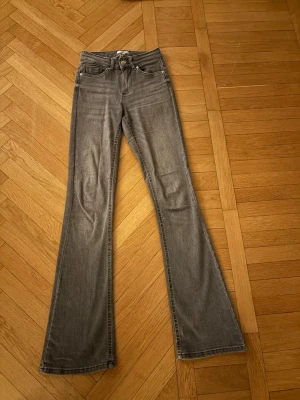Grå bootcut jeans med medel hög midja - Snygga grå jeans med bootcut-modell och medel hög midja. Jeansen har klassisk femficksdesign och är tillverkade i mjukt denimtyg🩷