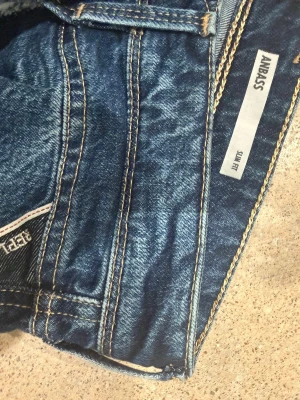 Replay Anbass jeans i blå denim - Snygga Replay Anbass jeans i klassisk blå denim med coola kontrastsömmar och detaljer på bakfickan. Jeansen har en modern passform och är perfekta för dig som gillar stilrena men ändå unika jeans. Materialet är slitstarkt och bekvämt. Byxorna är aldrig använde mer än att jag testat dem och tagit bort prislappen.