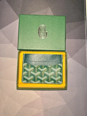 Grön Goy4rd plånbok - Snygg grön plånbok från Goy4rd i skinn med det klassiska grafiska mönstret i vitt och grönt. Slimmad design med flera kortfack, perfekt för dig som vill ha stilren och exklusiv känsla i fickan. Kommer i original ask.