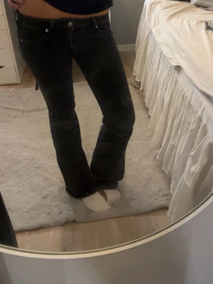 Svarta bootcut jeans  - Säljer ett par svarta jeans  med klassisk femficksdesign och bootcut-ben. Jeansen har en snygg mörk tvätt och normal passform, perfekt för dig som gillar en tidlös look. Materialet är slitstarkt jeans och midjan är lowwaist.