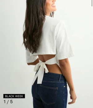 Vit croppad topp med knyt i ryggen - Knyt topp från Nelly, fint skick! Storlek M men går att knyta åt så tajt som man vill ha den