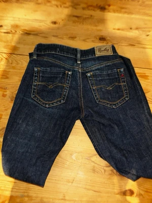Replay Pearl mörkblåa  - Snygga mörkblå jeans från Replay, modell Pearl. Klassisk femficksdesign med kontrastsömmar och Replay-logga på bakfickan samt metallmärke vid framfickan. Jeansen har rak passform och är tillverkade i slitstarkt denimtyg. Dem är ganska så slim