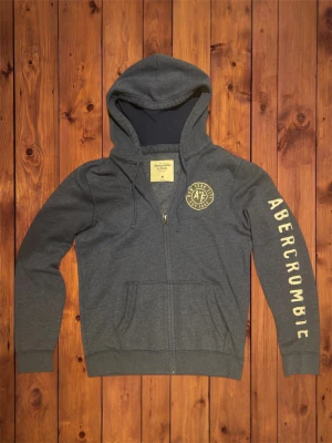 Vintage Abercrombie&Fitch Zip-Up Hoodie (sällsynt) - Säljer denna vintage sällsyna och asfeta zip-up hoodien från Abercrombie&Fitch. Den är riktigt fet och har ett väldigt snygg logga på armen. Storlek är M den passar som M och se måtten nedan. B=69cm A=54cm