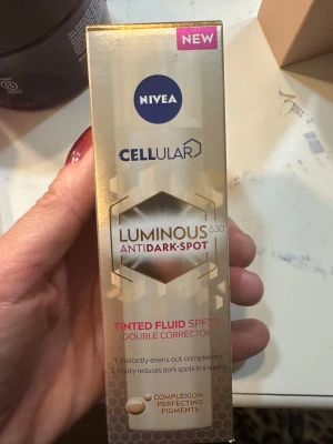 NIVEA Cellular Luminous630 Tinted Fluid - NIVEA Cellular Luminous630 Anti Dark-Spot Tinted Fluid SPF20 är en flytande foundation med dubbelkorrigerande effekt. Den har en ljusbeige ton, ger naturlig täckning och jämnar ut hudtonen. Innehåller hyaluronsyra och pigment som minskar mörka fläckar. Kommer i en pumpflaska.helt ny oöppnad, dagkräm 