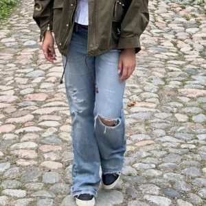 Ljusblå bootcut jeans med slitningar - Säljer ett par ljusblå jeans med bootcut passform och snygga slitningar på knä och fickor. Det finns ett litet hål/spricka på baksidan.❤️