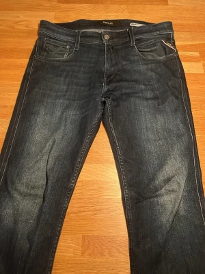 Replay Anbass jeans mörkblå slim fit - Snygga Replay Anbass jeans i mörkblå tvätt. Slim fit-modell i storleken 30/32.  Jeansen har en stilren look och är tillverkade i mjukt jeansmaterial som sitter skönt och är väldigt strechigt. Jeansen har mindre slitningar på några ställen. Priset kan diskuteras då jag helst bara vill bli av med dem. 