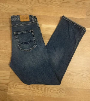 Blå Replay Thad jeans - 16A - Jag säljer dom här riktigt snygga Replay Thad jeansen som är i storlek 16A. Enda defekten är att det är hål i höger framficka. Annars är de i fint skick. Tveka inte att höra av er!                                Mått: Längd=98cm. Midja=37cm