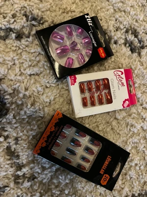 Tre paket lösnaglar i olika färger - Säljer tre paket lösnaglar: ett med metallic rosa från Ztiz Beauty, ett med glansigt röd från Glam of Sweden och ett med svarta naglar med röd glittertopp och halloweenmotiv. Alla är gjorda av plast. Lim kmr tyvärr it att skickas med💕
