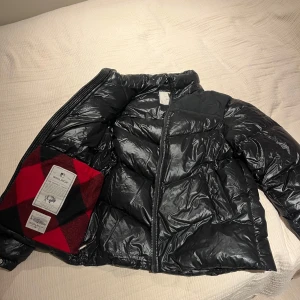 Svart pufferjacka från Woolrich - .Säljer en Woolrich vinterjacka i stl M. Klassisk look, varm och bekväm med det röda/svarta rutiga fodret. Sitter snyggt och funkar perfekt för riktigt kalla dagar. En liten lagning på ärmen (syns knappt, se bild), annars i fint skick. En kvalitetsjacka som håller värmen ordentligt. Hör av dig om du vill ha fler bilder eller mått!