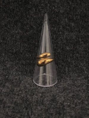 Goutte d’Or - Justerbar ring i guldpläterat rostfritt stål där två mjuka droppformer möts i en stilren silhuett.