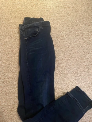 Mörkblå Replay jeans, storlek 32/33 - Snygga mörkblå jeans från Replay i klassisk femficksmodell. Jeansen har raka ben och normal passform, med midwaist och diskreta slitningar för en cool look. Materialet är slitstarkt jeans och färgen är djup marinblå. Perfekt för dig som gillar stilrena och tidlösa jeans.