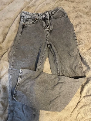 Grå straight jeans från Denim - Snygga grå jeans från Denim med klassisk femficksdesign och raka ben. Jeansen har hög midja, silverfärgade knappar och en ljus tvätt som ger en cool vintagekänsla. Perfekta för dig som gillar en avslappnad och tidlös stil.