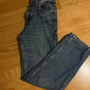 Blå jeans Jack & Jones Regular Clark - Säljer ett par klassiska blå jeans från Jack & Jones, modell Regular Clark. Jeansen har rak passform, fem fickor och snygga kontrastsömmar. Materialet är slitstarkt denim och midjan är normal. Perfekt för dig som gillar tidlös stil.