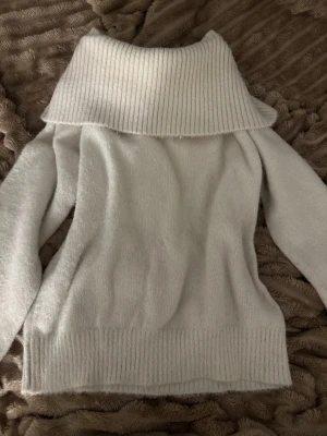 Vit polotröja med bred krage - Mysig vit polotröja med extra bred, ribbad krage som ger en chill och trendig vibe. Tröjan är stickad och har långa ärmar samt ribbade muddar vid nederkant och krage. Perfekt för att hålla sig varm och se snygg ut under kyliga dagar. Den är i strl 152, men passar mig jätte bra som brukar ha S/Xs