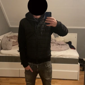 Svart cardigan - Svart bomberjacka från Barbour international med quiltad front i syntetmaterial och stickade ärmar och rygg. Jackan har dragkedja framtill, ribbade muddar och två fickor med dragkedja. Enkel och clean stil som passar perfekt till jeans. Nypris 2000 +, säljs inte längre ny.