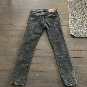 Levi's 502 svarta jeans W29 L32 - Svarta Levi's 502 jeans med klassisk femficksdesign och rak passform. Jeansen har en snygg tvättad look och är tillverkade i slitstarkt denim. Perfekt för dig som gillar en enkel och stilren vibe. Läderpatch med logga baktill.