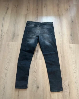 Supply & Demand svarta skinny jeans XL - Svarta skinny jeans från Supply & Demand i storlek XL med slitna detaljer och coola hål på knäna. Jeansen har en mörk tvätt och är tillverkade i stretchigt denim för en tajt passform. Perfekt för dig som gillar streetstyle och edgy look.