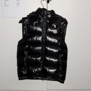 Svart dunväst från Moncler - Säljer denna feta stilrena Moncler väst, Storlek 2 vilket motsvarar S, västen är i mycket bra skick nästan som helt ny, säljer pga jag har växt ur den, perfekt för hösten och våren, tveka inte att ställa frågor. 