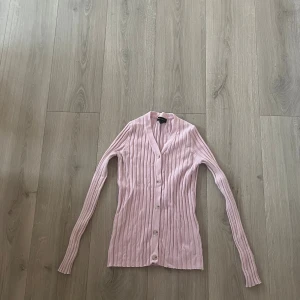 Ljusrosa ribbad kofta från QED London - Supersöt ljusrosa kofta från QED London i storlek XS. Den är ribbad med smala vertikala ränder, har lång ärm och knäpps med fyra genomskinliga knappar framtill. Koftan är figurnära och har en mjuk, tunn känsla som passar perfekt till lager-på-lager. Säg bara till om ni vill ha mått eller har några andra frågor!!💗💗