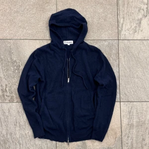 St studios hoodie - Mörkblå hoodie från St Studios i storlek XS. Tröjan har huva med snörning, dragkedja framtill och två fickor. 100% cashmere. Hör av dig vid funderingar!