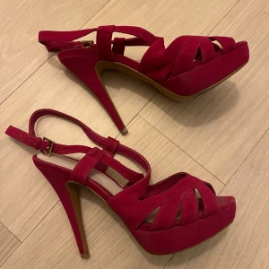  Cerise höga klackar från Bianco - Säljer ett par snygga klackar från Bianco med höga klackar och plattform. Skorna har öppna tår, justerbar rem med spänne och är tillverkade i mocka. 