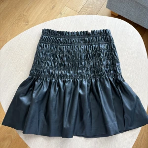 Svart kortkjol i skinnimitation Gina Tricot - Supersnygg svart kortkjol från Gina Tricot i skinnimitation. 