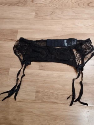 Svart strumpebandshållare i spets med rosetter - Säljer en svart strumpebandshållare från H&M i storlek S. Den har fina rosettdetaljer och justerbara band. Tillverkad i tunn spets med genombrutet mönster och hakknäppning bak. Perfekt för alla hjärtans dag  / Valentine's day. Jag har fler annonser uppe och ger mängd rabatt, så kolla gärna min sida!