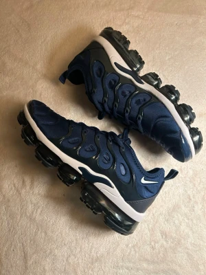 Nike Air VaporMax Plus i stilren mörkblå färg. - Säljer ett par Nike Air VaporMax Plus i stilren mörkblå färg. Helt nya och oanvända, med originalkartong.  ?? Storlek: EU 43 (US 9.5 / UK 8.5 / 27.5 cm) ? Skick: Nya ?? Färg: Mörkblå ?? Maxad komfort med VaporMax Air-sula ?? Originalkartong ingår  Perfekta både till vardag och streetwear – en tidlös modell som sticker ut.  ???? Fraktar snabbt  ?? Hör av dig vid frågor eller mer bilder