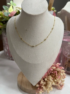 Guldpläterat halsband - Ett vackert och stilrent halsband tillverkat av rostfritt stål, pläterat med 18K guld. Halsbandet är vattentåligt och allergivänligt – perfekt för daglig användning.  De glittrande strass-stenarna (rhinestones) ger ett mjukt och feminint uttryck som passar både vardag och fest.  💛 Rostfritt stål 💛 18K guldplätering 💛 Vattentåligt & allergivänligt 💛 Strass / rhinestones