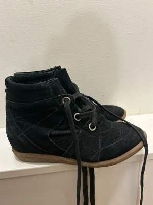 Svarta mockasneakers med klack  - Säljer ett par svarta sneakers men klack i mocka med högt skaft och snörning. Skorna har rund tå, platt sula och coola sömdetaljer. Smuts på tån gör att ta bort, gör det innan jag skickar