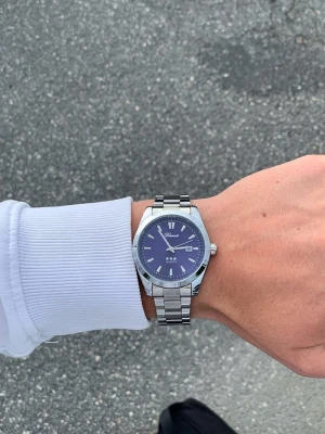 Silverfärgade blå klocka x Doventi  - Denna Doventi-klocka är helt ny och oanvänd, i toppskick och levereras komplett med originalbox. Den är garanterat utan defekter, har enkel justering för optimal passform och skickas samma dag som beställning.