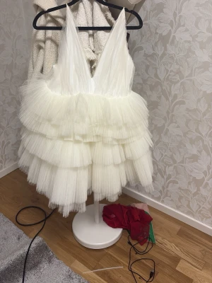 Vit volangklänning från true decandence - Säljer min supersöta vita studentklänning, kortklänning med flera lager av volanger i tyll och djup v-ringning. Klänningen har tunna axelband och är fluffig, Perfekt för dig som vill ha något extra till studenten. Jag har sytt banden då de va stor. Finns lite smink på men går bort. 