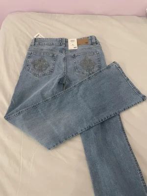 Lager 157 jeans - Ljusblå jeans från 157 i modellen Paris Embroidery. Byxorna har utsvängda ben, broderade detaljer på bakfickorna och dubbla knappar framtill. 