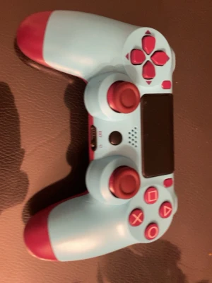 PlayStation 4 DualShock 4 Special Edition - Snygg DualShock 4-kontroll till PlayStation 4 i unik ljusblå och röd färgkombination. Kontrollens knappar och styrspakar ser ut att vara i fint skick utan synligt slitage. Perfekt för dig som vill ha en personlig touch på din spelupplevelse.