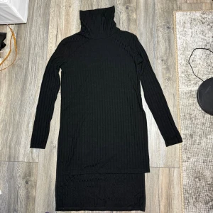 Svart ribbad polotröja från Crocker XS - Svart långärmad polotröja från Crocker i ribbat, tunt material. Tröjan är figurnära och har en hög polokrage som kan vikas ner. Perfekt till höst och vinter för en stilren look.