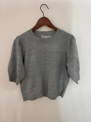 Grå stickad T-shirt  - En kortärmad stickad tröja med ballongarmar. Väldigt skönt material. Säljer då jag rensar min garderob ❣️ 