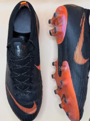 Nike Mercurial Vapor fotbollsskor - Säljer ett par svarta och orange Nike Mercurial Vapor i storlek 42. Inga synliga eller större skador på skorna så mycket bra skick på de. Pris kan självklart diskuteras 