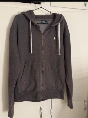 Grå zip hoodie Ralph Lauren - Zip hoodie från Ralph Lauren, mycket fint skick , 65 cm lång. Storlek M , passar 178-182 som bäst. Lägg till flera tröjor i bundle och få bra rabatt ✅
