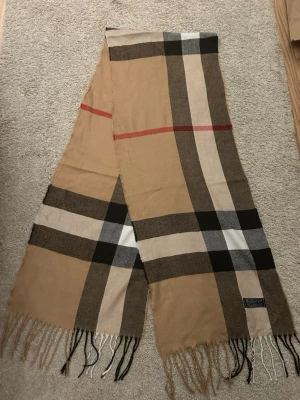 Burberry scarf - Klassisk rutig halsduk i Beige, svart, vit och röd färg med fransar i ändarna. Perfekt accessoar. Pris kan diskuteras!