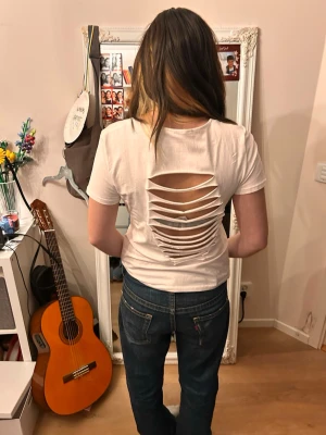 Snygg vit  T-shirt med cool rygg - En superfin T-shirt med coolt klippt rygg, storlek står inte men passar som S-M.                                           Tveka inte att höra av er! Pris kan diskuteras