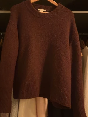 Vinröd stickad tröja - Mysig vinröd stickad tröja med rund hals och ribbade muddar. Perfekt för kyliga dagar och enkel att matcha med jeans eller kjol. Tröjan har en relaxed passform och är superbekväm att bära.