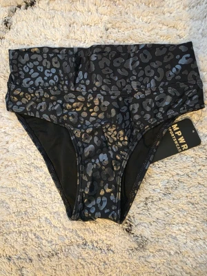 Helt ny leopardmönstrad bikiniunderdel MPWR - Snygg bikiniunderdel från MPWR Sportswear i svart med leopardmönster. Hög midja och sportig passform, perfekt för strand eller pool. Tillverkad i stretchigt syntetmaterial som sitter skönt och ger bra stöd.