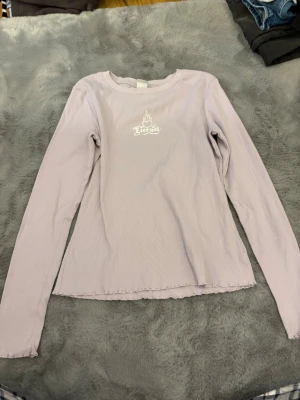 Ljuslila ribbad långärmad topp Lindex - Ljuslila ribbad långärmad topp från Lindex med tryck 'Eternal' och en brinnande hjärta på bröstet. Toppen har en figurnära passform och vågig kant nertill för en extra detalj. Perfekt till dig som gillar en enkel men cool stil.