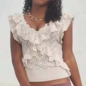Beige stickad volangtopp från zara - Supersöt beige stickad topp från Zara med breda volanger längs axlar och bröst. Toppen är ärmlös, har v-ringning och ett detaljerat spetsliknande mönster. Perfekt för dig som gillar romantisk och vintage-inspirerad stil. Pris kan diskuteras!